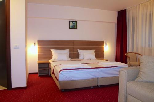 um quarto de hotel com uma cama e um sofá em Hotel Carpați em Predeal
