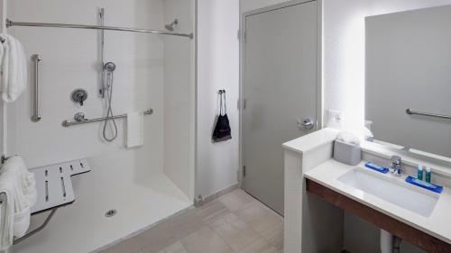 a white bathroom with a shower and a sink at Holiday Inn Express & Suites Orlando At SeaWorld by IHG - With Free Shuttle Service to SeaWorld Parks in Orlando