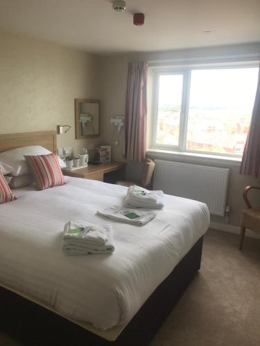 1 dormitorio con 1 cama grande y toallas. en Monarch Hotel, en Bridlington