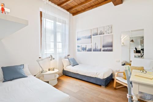 a white room with two beds and a desk at Florence City Center Flat Via Dei Neri in Florence