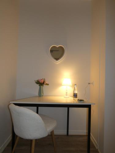 a table with a chair and a lamp and a heart shaped mirror at Hôtel Restaurant le clos de l 'Ancien Pressoir in Commes