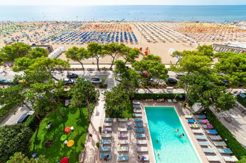 an aerial view of a beach with a pool and beach umbrellas at Hotel American in Lignano Sabbiadoro