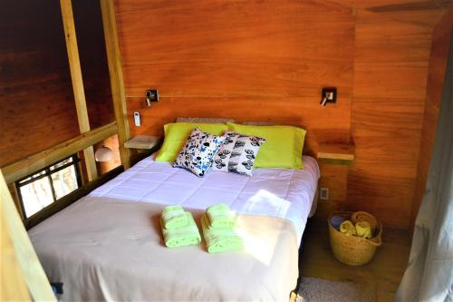 een bed in een kamer met twee groene slippers erop bij El cabañon del cuervo in Punta Del Diablo