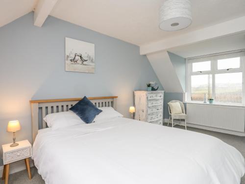 Un dormitorio con una gran cama blanca y una ventana en The Granary - Rhoscolyn, en Holyhead