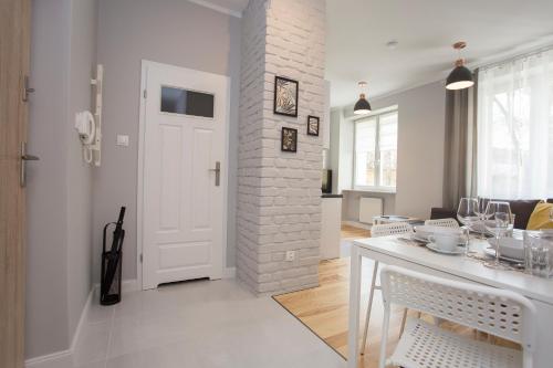 a kitchen and dining room with a white brick wall at CR Apartament przy Katedrze in Białystok