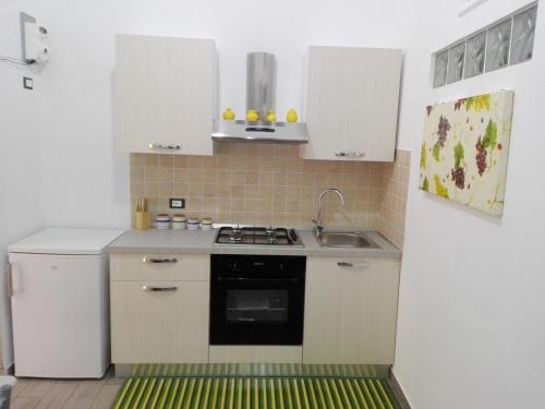 a kitchen with white cabinets and a stove and a refrigerator at Casa Solferino in Marsala