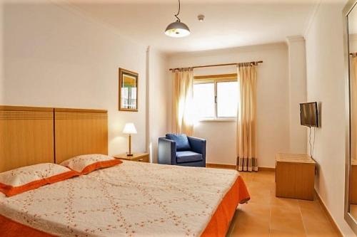 a bedroom with a large bed and a blue chair at Veleiro Verde in Monte Gordo