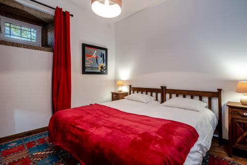 a bedroom with a large bed with a red blanket at Quinta das Lamas - Antiga Adega in Vouzela