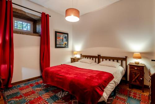 a bedroom with a large bed with red curtains at Quinta das Lamas - Antiga Adega in Vouzela