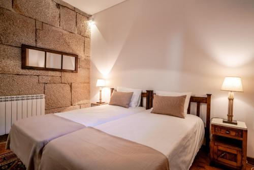 a bedroom with two beds and a brick wall at Quinta das Lamas - Antiga Adega in Vouzela