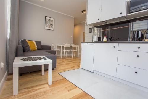 eine Küche und ein Wohnzimmer mit einem Sofa und einem Tisch in der Unterkunft CR Apartament przy Katedrze in Białystok