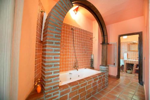 y baño con bañera en una pared de ladrillo. en Casa Rural Las Gamellas, en Rebollar