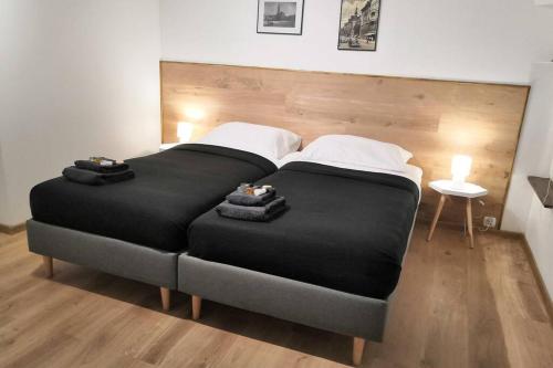 a bedroom with a large black bed with a wooden headboard at OficynaApartments in Gliwice