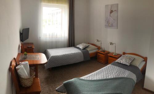 a bedroom with two beds and a table and a window at Gościniec Rutikal in Sianów