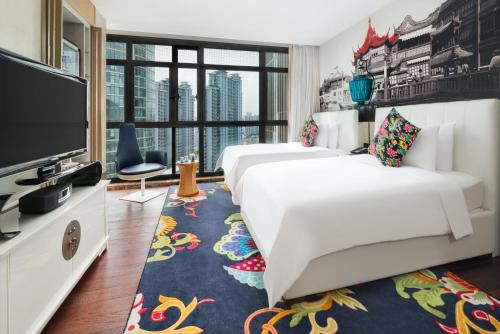a hotel room with two beds and a flat screen tv at Hotel Indigo Shanghai On The Bund by IHG in Shanghai