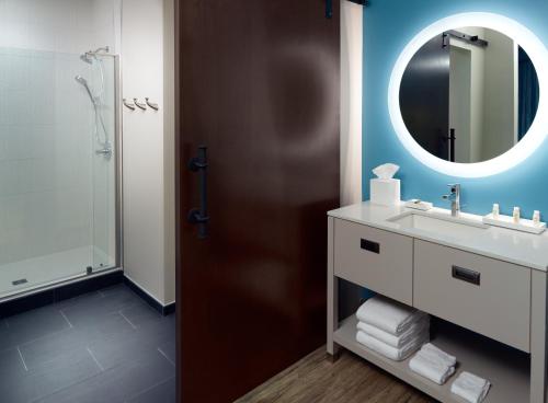 a bathroom with a mirror, sink, and toilet at Hotel Indigo Tuscaloosa Downtown, an IHG Hotel in Tuscaloosa