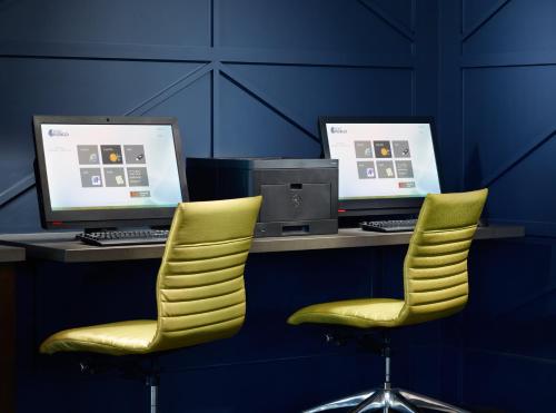 two yellow chairs and two computer monitors on a desk at Hotel Indigo Tuscaloosa Downtown by IHG in Tuscaloosa