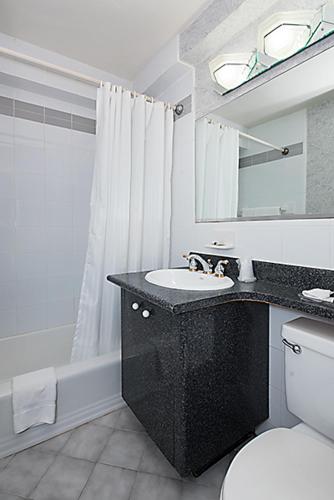 a bathroom with a sink and a toilet and a mirror at Murray Hill East Suites - Extended Stay in New York