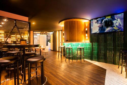 a restaurant with a bar with stools and a tv at Hotel Indigo Madrid - Gran Vía by IHG in Madrid