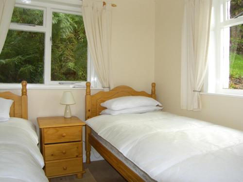 2 Betten in einem Schlafzimmer mit 2 Fenstern in der Unterkunft Roddy's Cottage in Glenelg