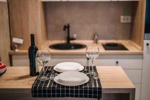 a table with two plates and wine glasses on it at Apartments Doclea in Podgorica