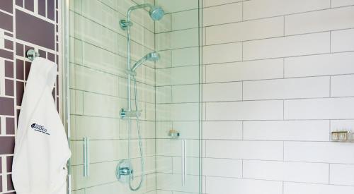 a bathroom with a shower with a glass door at Hotel Indigo Savannah Historic District by IHG in Savannah