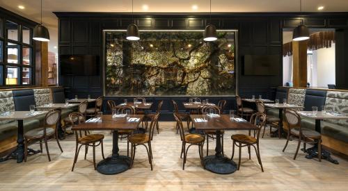 a dining room with tables and chairs and a painting at Hotel Indigo Savannah Historic District by IHG in Savannah