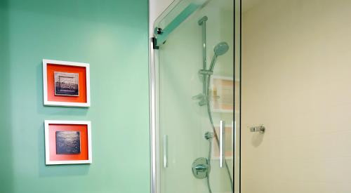 a shower in a bathroom with pictures on the wall at Hotel Indigo Savannah Historic District by IHG in Savannah