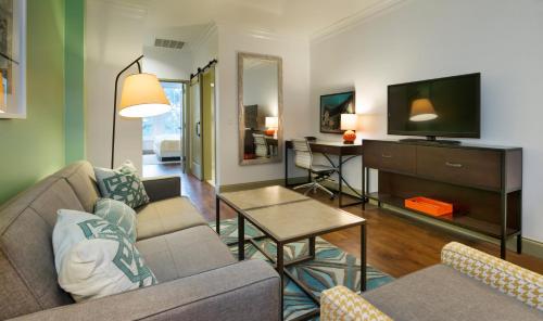 a living room with a couch and a tv at Hotel Indigo Savannah Historic District by IHG in Savannah