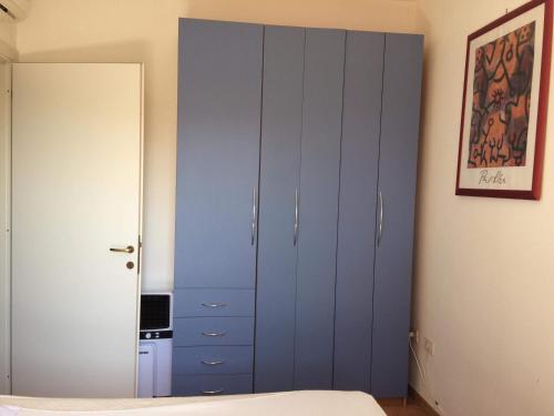 1 dormitorio con armario azul y cama en Airport at 25 min by walk - 5 min by walk to commercial center 2 min by walk to touristic port for trip to islands 5 min by walk to bus for city and beaches -Balcony sunset and Sea view-wi fi-air cond-5 persons-pool from 15 june to 15 september PISCINA en Olbia