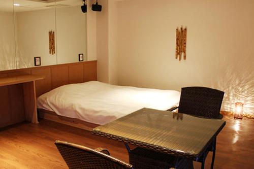 海南市的住宿－海南女王酒店，配有一张床和一张桌子及椅子的房间