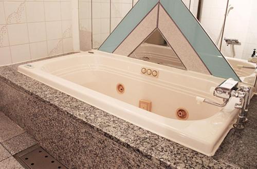 bañera con espejo encima de una encimera en Sea Queen Kainan, en Kainan
