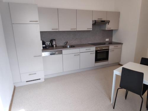 a white kitchen with white cabinets and a table at Flataid Apartment Reitschulgasse - City Center - Jakominiplatz in Graz