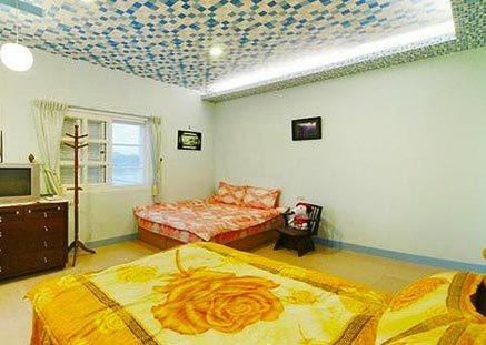 a bedroom with two beds and a ceiling decorated with at Harmony Village in Wujie