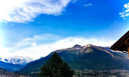 a view of a mountain with a tree and a city at Agriturismo B&B Chèvres à Cheval in Aosta