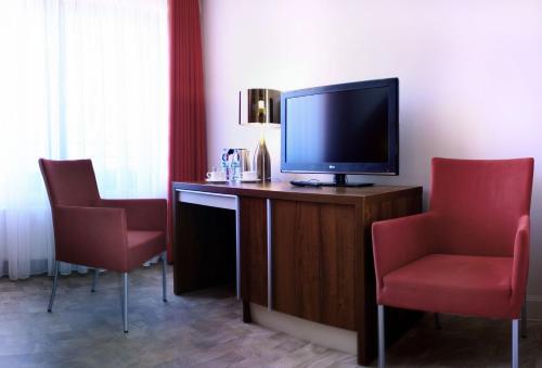a hotel room with a television and two chairs at Apartamenty Mesa Grill Restaurant Cafe in Dźwirzyno