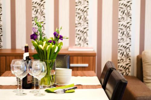 a table with a vase of flowers and wine glasses at 6 Apartments in Predeal