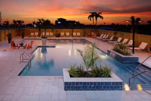 a swimming pool with chairs and a sunset in the background at Hotel Indigo Orange Beach - Gulf Shores by IHG in Gulf Shores