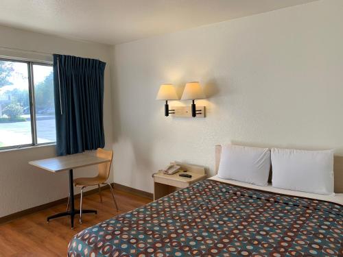 a hotel room with a bed and a desk and a window at Vagabond Inn Sylmar in Sylmar