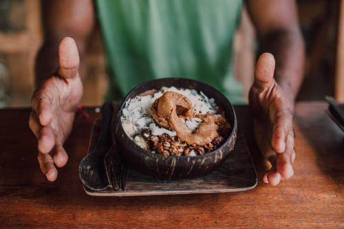 a person is holding a bowl of food with a pretzel at Flowers & Fire Yoga Garden in Gili Air