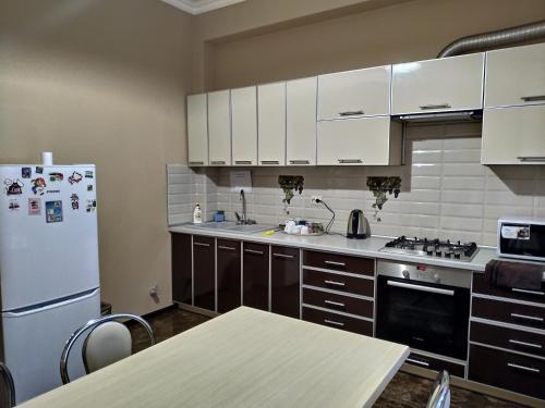a kitchen with white cabinets and a refrigerator at Отель Ялос | Симферополь, Крым in Simferopol