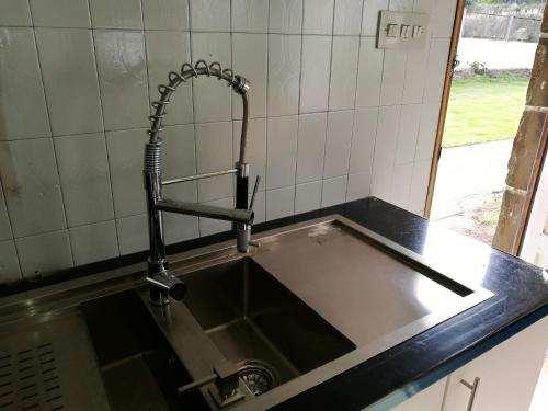 - un évier avec un robinet dans la cuisine dans l'établissement Casa a pié de playa de Cariño Doniños, à Ferrol