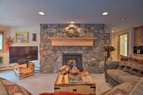 a living room with a stone fireplace with a tv at Fall River Hideaway in Estes - 3 Mi to Natl Park! in Estes Park