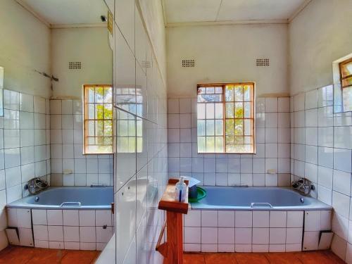 a bathroom with two tubs and two windows at Blend Lodge and Kitchen - Pakachere in Zomba