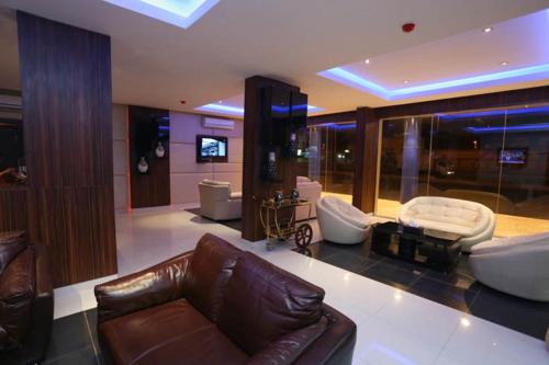 Una sala de estar con un sofá y sillas de cuero marrón. en رؤوم إن للشقق المخدومة - Raoum Inn Serviced Apartments-Hotah, en Hotat bani tamim