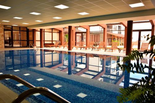 a swimming pool in a building with tables and chairs at Royal Bansko - Half Board Plus & All Inclusive - Hot Pool & Jacuzzis in Bansko