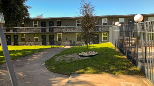 a building with a fence and a tree in a yard at Motel 6-Temple, TX in Temple