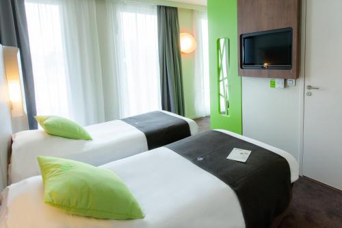 a hotel room with three beds and a flat screen tv at Campanile Rennes Sud - Saint Jacques in Saint-Jacques-de-la-Lande