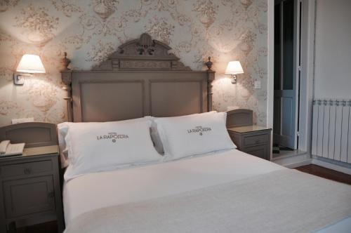 una camera da letto con un grande letto con due cuscini bianchi di Hotel Rural La Raposera a Caravia