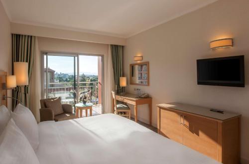 
a hotel room with a bed, tv and a window at Radisson Blu Resort & Spa Cesme in Çeşme
